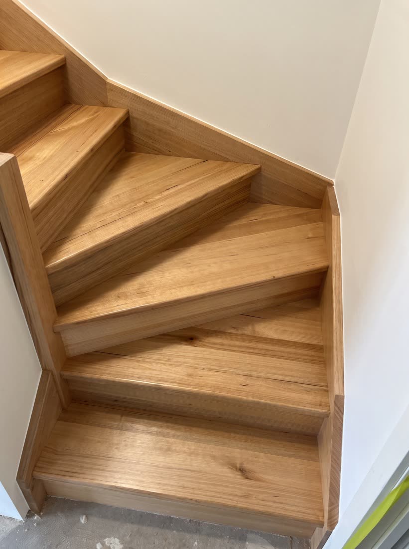 Timber winder treads turning a corner, each tread set out to converge at the newel